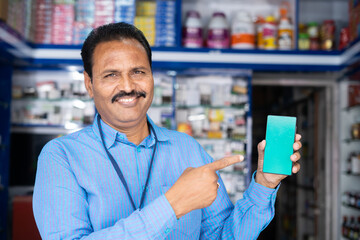 smiling medical shop owner showing green screen mobile phone by looking at camera - concept of epharmacy, making online order,app advertisement and promotion.