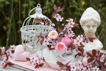 romantische Frühlingsdekoration mit Blumenstrauß von Maßliebchen und Blüten der Japanischen Zierkirsche