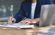© Wasan - Accountant or banker working process, a Businessman using a calculator to calculate the numbers of statistic business profits growth rate on documents graph data, his desk in an office.