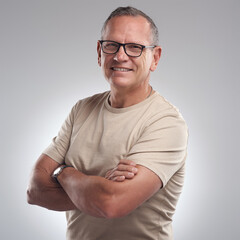 My dress sense is relaxed with a hint of style. Shot of a handsome mature man standing alone against a grey background in the studio with his arms folded.