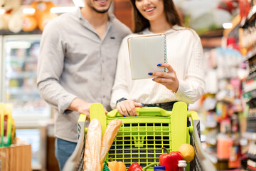 Wall Mural - Unrecognizable Couple Holding Grocery Shopping List Buying Food In Supermarket