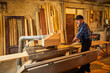 © bondvit - Wood cutting table with electric circular saw.  Senior Professional carpenter in uniform cutting wooden board at sawmill carpentry manufacturing . Sawing machine