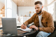 © Prostock-studio - Bearded Business Man Taking Notes Using Laptop Sitting At Home