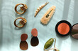 Coral blush, jade roller, pearl barrettes and gold earrings on bright blue background. Flat lay.