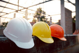 Fototapeta Sypialnia - Safety helmet (hard hat) for engineer, safety officer, or architect, placed on cement floor with brick background. White, Yellow and Orange safety hat (helmet) in construction site.