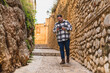 Chico con camisa cuadros blanca posando y tomándose fotos en callejón de piedra en pueblo blanco andaluz