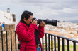 Chica joven guapa grabando con cámara y tomando fotos en pueblo blanco andaluz