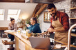 © Drazen - Young man cooks for his friends while following recipe on laptop in the kitchen.