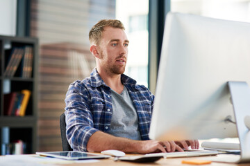 Working hard to maintain an edge as a leading designer. Cropped shot of a young designer working on a computer in an office.