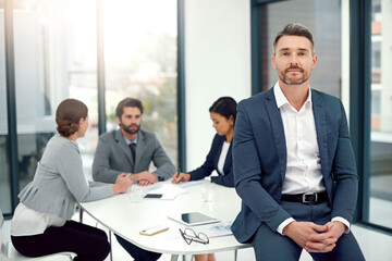 Wall Mural - We all value each others expertise. Portrait of a businessman standing in a boardroom meeting with colleagues in the background.