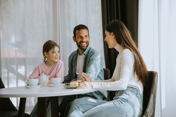 Happy young famila eat cakes and drink tea together