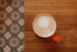 Fototapeta Mapy - A cup of fragrant fresh latte coffee on a wooden table in a modern cafe. Flat lay