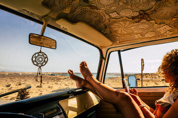 Interior of classic van camper with beautiful legs of woman stretched and relaxed. Travel people lifestyle concept. Summer holiday vacation and vanlife. Dreamcatcher and beach view holiday vacation