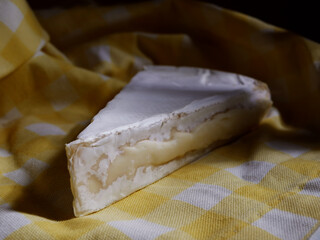 Slice of french brie cheese on yellow background