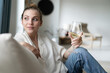 Successful young beautiful woman sitting on a sofa in the living room, drinking wine