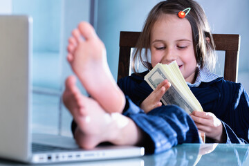 Wall Mural - Conceptual image: making money and good business. Beautiful young girl put her feet up on a table and plays with US Dollar money. Horizontal image.