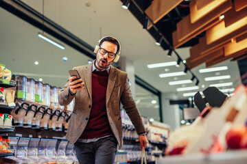 Wall Mural - Young man with earphones on enjoying shopping