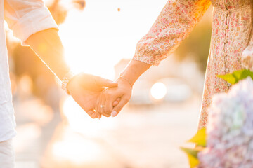 hands of a loving couple on a sunset background