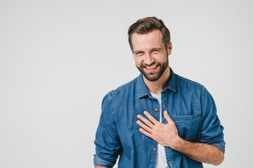 Happy young caucasian man in denim clothes laughing, touched with a compliment, good sense of humor isolated in white background