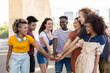 © Xavier Lorenzo - Group of young student friends with hands on stack showing international unity. United multiracial students standing together in city street - Community concept