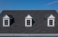 Closeup View Of Three White Dormer Windows On A Classic Roof With Blue Sky Background