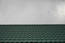 Roof Of House Against Background Of Gray Sky. Green Roof Tiles.