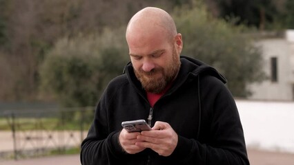 Handsome man at home using cell phone. He is very focused on the content of the message