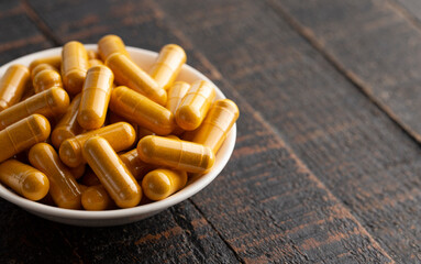 Wall Mural - Ground Turmeric Capsules form on a Wooden Table