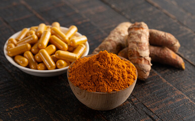 Wall Mural - Ground Turmeric Capsules form on a Wooden Table