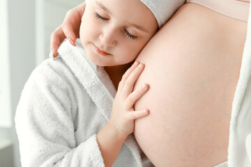 Wall Mural - Little girl with her pregnant mother at home in morning