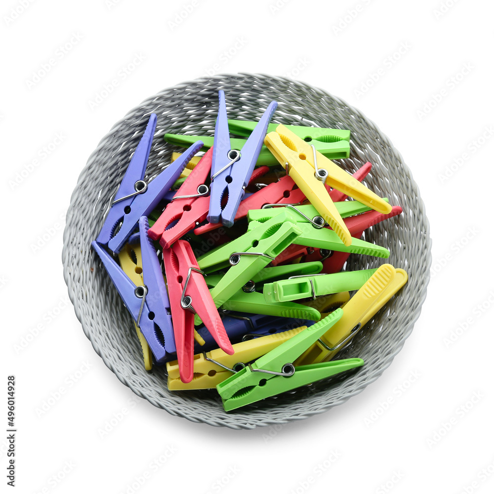 Wicker bowl with plastic clothes pins on white background