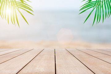 Empty wooden table in front of blurred beautiful view of the sea, sand, sunlight, palm tree background of nature with copy space in summer. Can be used for display or montage for show your products.