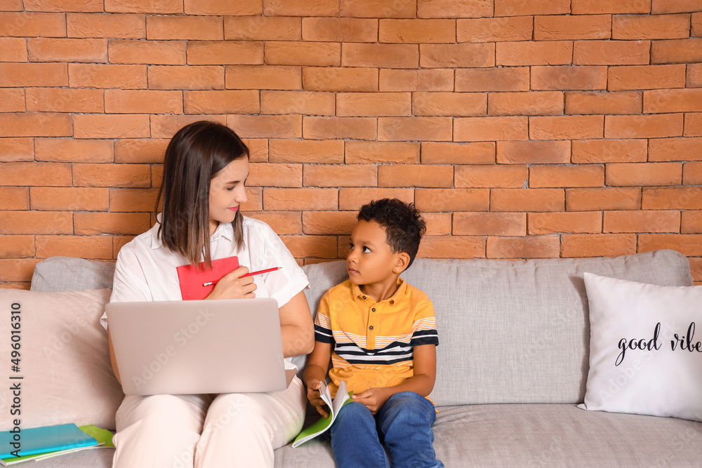 Little African-American boy studying with tutor at home