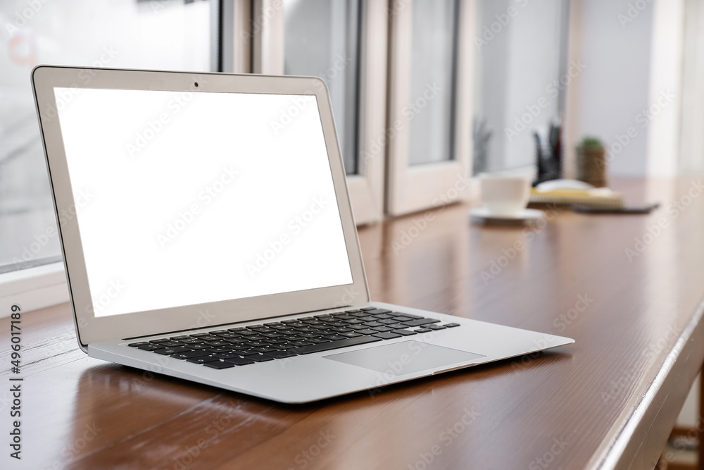 Modern laptop on wooden table near window