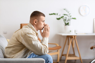 Sticker - Troubled young man sitting on sofa at home