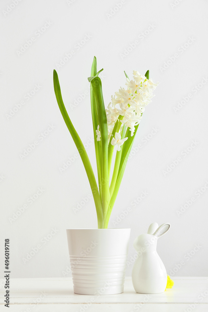 Pot with beautiful hyacinth plant and Easter bunny on light background