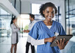 © Delmaine Donson/peopleimages.com - Our patient records are all digitized. Shot of a young doctor using a digital tablet in a hospital with her colleagues in the background.