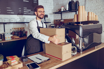 Cheerful male worker receiving package delivery in cafe