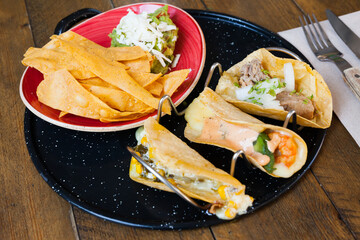 Wall Mural - Delicious Mexican set of tacos with carnitas, shrimps and corn and crispy nachos with guacamole