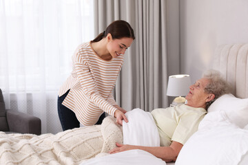 Wall Mural - Young caregiver and senior woman in bedroom. Home health care service