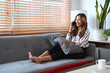 © Prathankarnpap - Beautiful asian woman sitting on sofa and talking on mobile phone, spend leisure time at home.