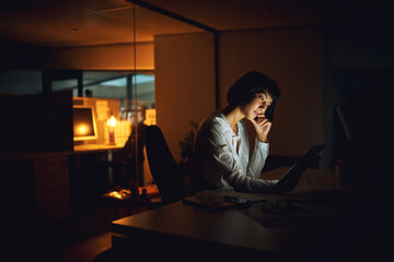 Poster - Getting it done after dark. Shot of a young businesswoman using a digital tablet during a late night at work.