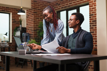 Department team leader pointing out on laptop screen financial data and management chart. Confident businessman talking with coworker about startup project marketing strategy.