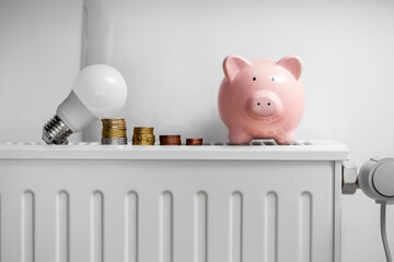 Wall Mural - heating, energy crisis and consumption concept - piggy bank, light bulb and money on radiator at home