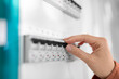 © Syda Productions - electricity, energy and power consumption concept - close up of hand switching electric board at home