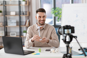 Wall Mural - distance education, school and green energy concept - happy smiling male teacher with camera and wind turbine model having online class at home office