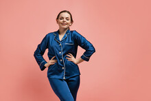 Portrait Of Young Smiling Woman In Blue Silk Pajamas Posing Isolated Over Pink Studio Background