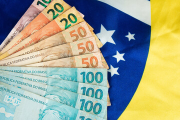 Brazilian money banknotes with Brazilian flag in the background