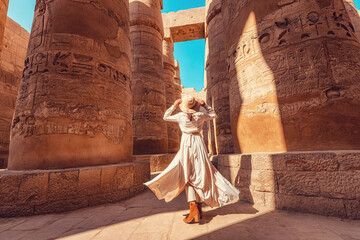 Wall Mural - Woman traveler explores the ruins of the ancient Karnak temple in the city of Luxor in Egypt. Great row of columns with carved hieroglyph