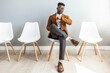 © Dragana Gordic - Full length shot of a handsome young businessman sitting and looking down at his watch against a gray studio background. I'm getting bored waiting for them